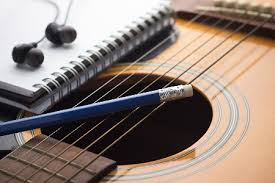 notebook and headset on top of an acoustic guitar